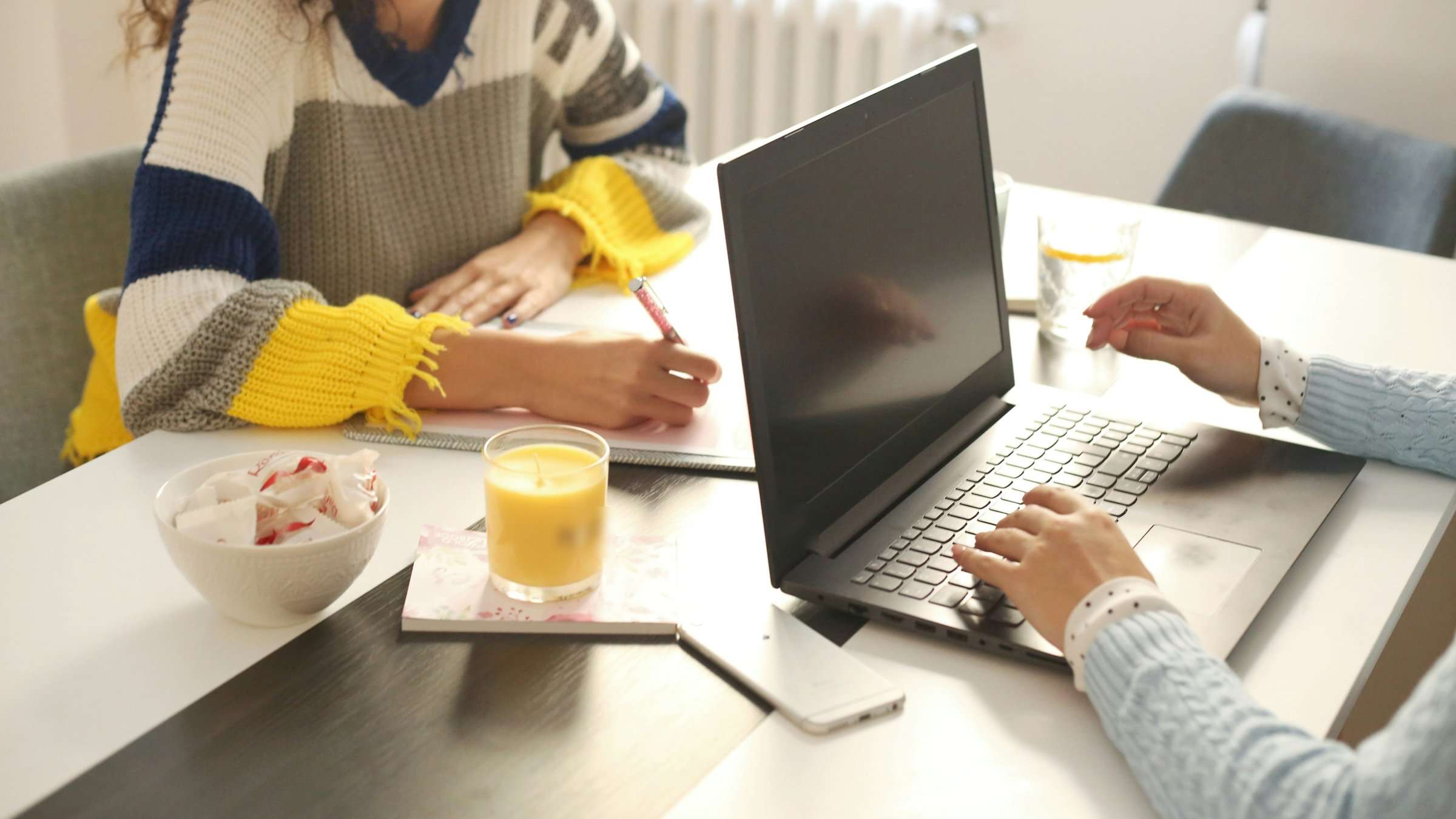 Unas manos alrededor de una mesa, con papeles y un ordenador portátil.