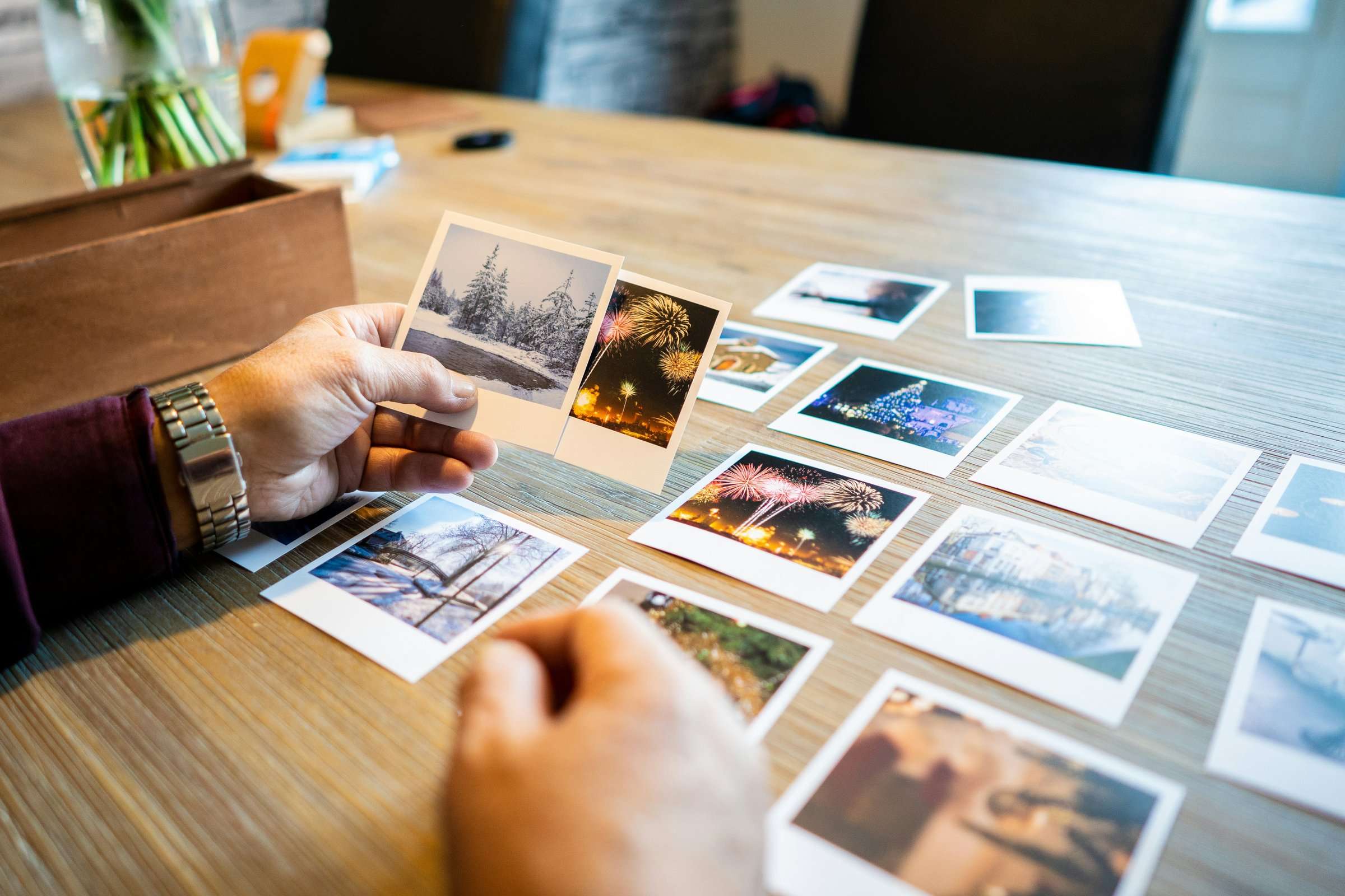 Manos de una persona mayor ordenando fotografías sobre una mesa.